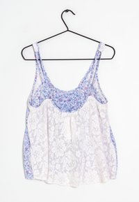 Top in pizzo con stampa floreale nei toni di blu, realizzato in un tessuto leggero, con spalline regolabili e una vestibilità ampia. Sovrapposizione di pizzo bianco.
