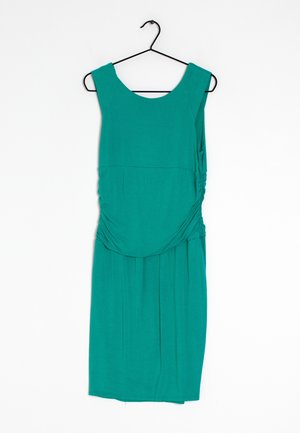 Robe sans manches teal avec un décolleté arrondi et des côtés froncés, suspendue à un crochet noir sur fond blanc. Texture lisse.