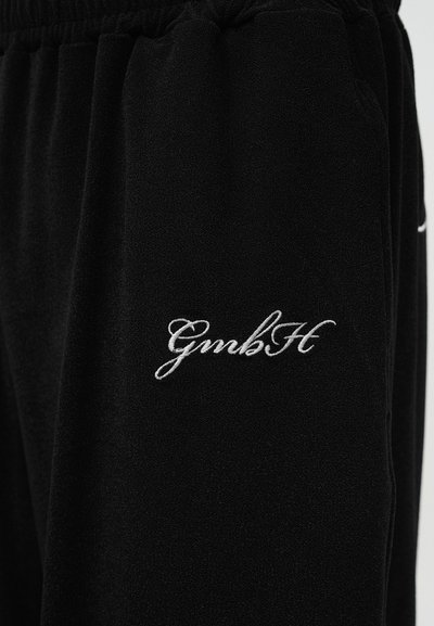 Μαύρο παντελόνι από φλις με ελαστική ζώνη μέσης και άσπρο κεντημένο στυλιζαρισμένο κείμενο "GmbH" στο μηρό.