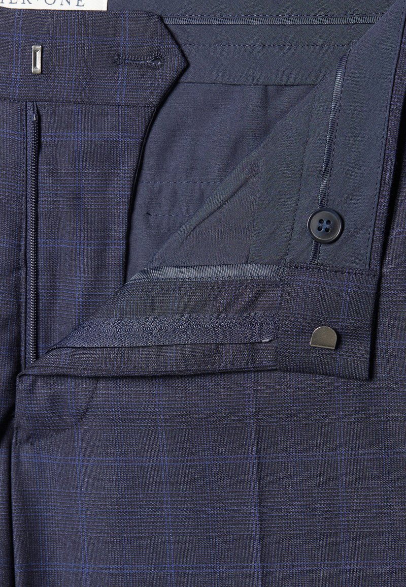 Pantalon bleu marine à motif carreaux, avec fermeture éclair, bouton et poches latérales. Le tissu a une texture lisse.