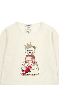 Cream long-sleeve shirt featuring a bear with a glitter crown and striped sweater, holding a red teddy bear below. Soft cotton fabric.