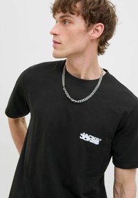Schwarzes Baumwoll-T-Shirt mit rundem Halsausschnitt und kurzen Ärmeln, mit einem weißen Logo auf der linken Brustseite bedruckt.