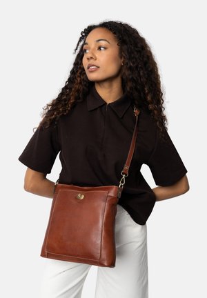 Hnědá kožená crossbody taška jednoduchého obdélníkového tvaru, s magnetickým uzávěrem a nastavitelným popruhem. Hladký povrch s jemnými švy.