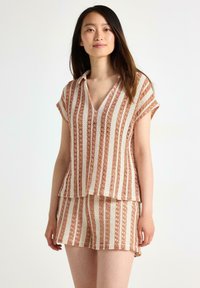 Stickad tvådelad outfit med V-ringning, korta ärmar och horisontella ränder i mjuk persika och grädde med en öppen vävstruktur.