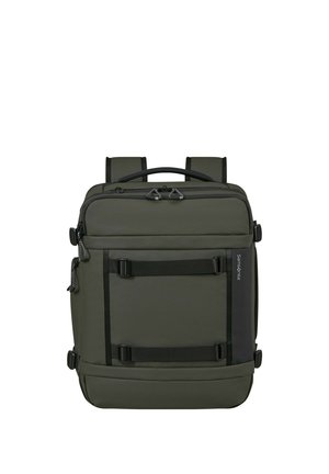 Quadratisch geformter dunkelgrüner Rucksack mit doppeltem Reißverschluss, schwarzen Trägern vorne, gepolsterten Schultergurten und einem oberen Griff.