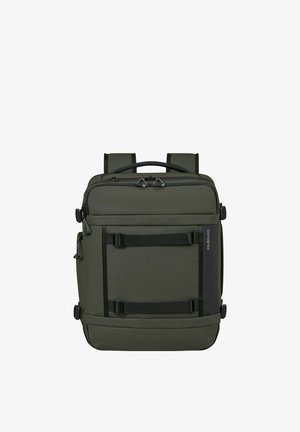 Square-shaped dark green backpack with dual zippers, black straps on front, padded shoulder straps, and a top handle.