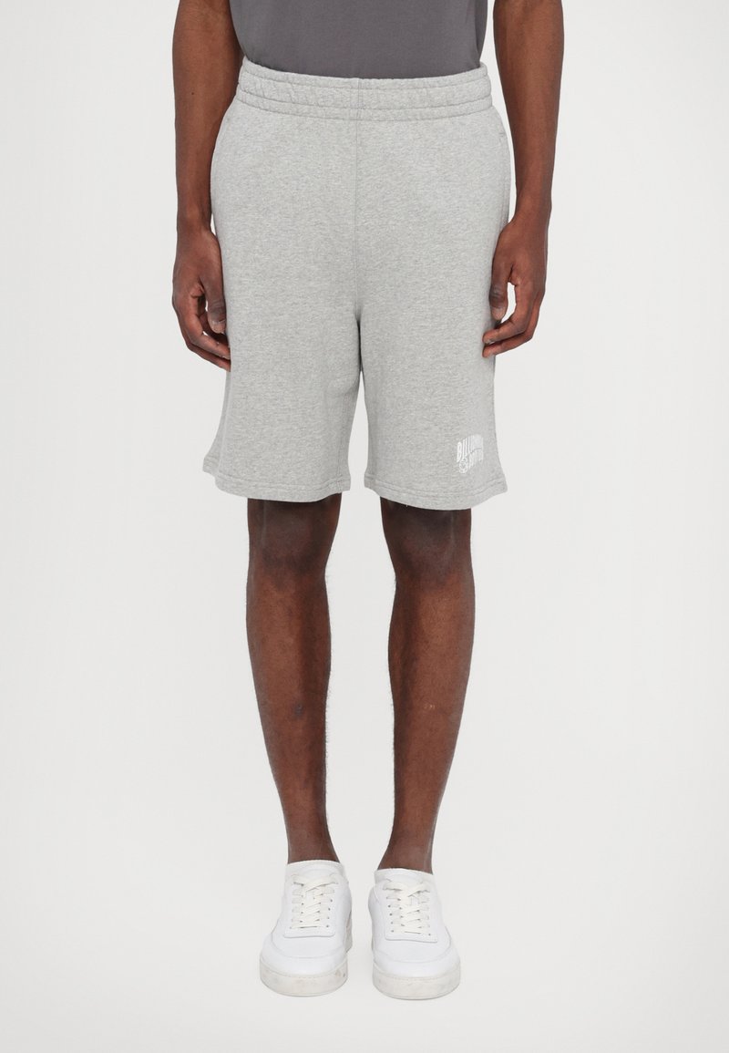 Grå bomuldsshorts med elastisk talje, sidelommer og et trykt logo på den nederste kant. Stylet med hvide sneakers.