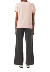 Light pink cotton t-shirt with short sleeves, paired with dark gray wide-leg jeans. Notable contrast in colors and textures.