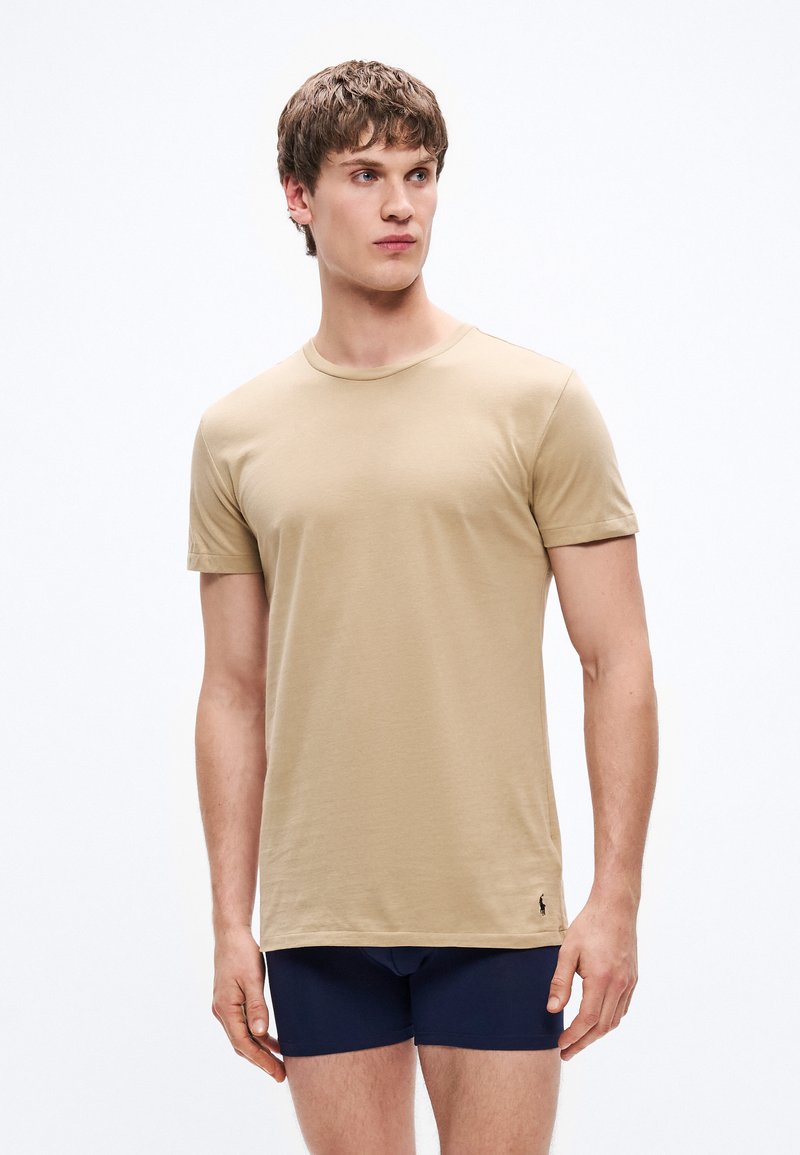 Μπεζ βαμβακερό T-shirt με στρογγυλή λαιμόκοψη και κοντά μανίκια, με στενή εφαρμογή και διακριτικό λογότυπο της μάρκας κοντά στο τελείωμα.