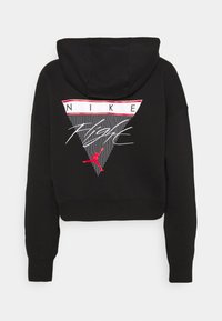 Sudadera corta negra con capucha, que presenta un estampado gráfico triangular con el texto "NIKE" y un logo de Jumpman rojo en la parte posterior.