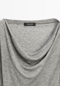 Top grigio drappeggiato realizzato in tessuto morbido. Presenta un ampio scollo e un'etichetta con la scritta "Massimo Dutti". Tessuto liscio con sottili variazioni.