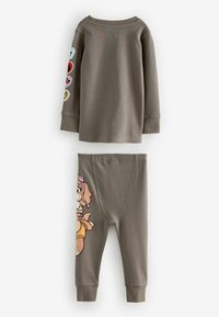 Tvådelad outfit som består av en långärmad, olivgrön topp med färgglada lappar och matchande leggings med en tecknad hundgrafik på ett ben.
