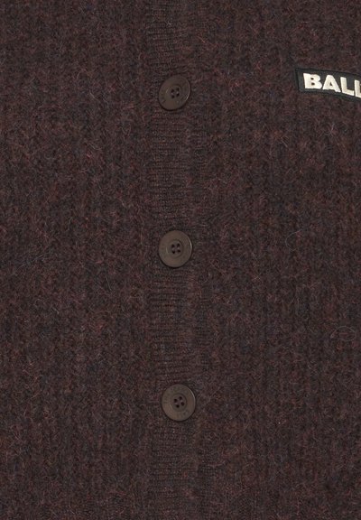 Brązowy sweter dzianinowy z czterema guzikami i teksturowanym wzorem. Zawiera naszywkę z logo z białym napisem "BAL".