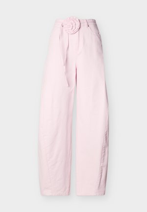 Ροζ ανοιχτού χρώματος παντελόνι με ευρύ πόδι και ψηλή μέση, με ζώνη από ύφασμα με λουλούδι και μπροστινές τσέπες, σε απλό γκρι φόντο.