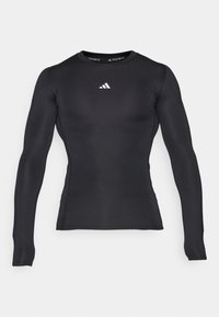 Sort langærmet atletisk kompressionsskjorte med rund hals og hvid Adidas-logo centreret på brystet.