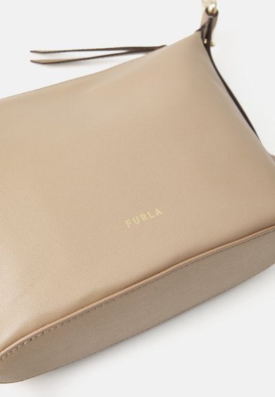 Sac bandoulière en cuir beige avec une texture lisse, logo doré "FURLA" et une fine bandoulière latérale. Design minimaliste avec une forme rectangulaire.