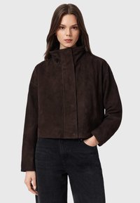 Giacca corta in camoscio marrone con collo alto e maniche lunghe, dotata di chiusura frontale con dettaglio di cucitura a vista.