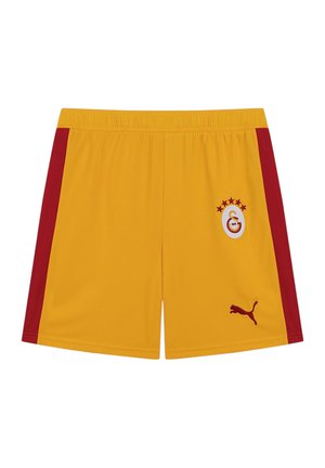 Shorts de sport jaunes avec des bandes rouges sur les côtés, arborant le logo du club de football Galatasaray et le logo Puma à l'avant.