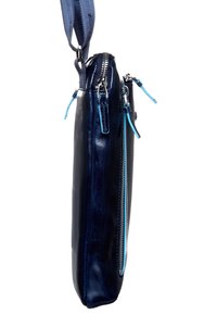 Borsa a tracolla in pelle blu navy con un design slim, dotata di zip metalliche, dettagli blu e una finitura testurizzata. Include una tracolla regolabile.