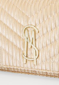 Quilting gullfarget stoff clutch-veske med gulllogo. Designet inkluderer vertikale striper og en glatt tekstur med metallisk glans.
