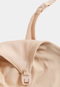 Cerniera in beige con hardware regolabile, tessuto liscio e cuciture ordinate sui bordi. Metà della coppa è piegata.