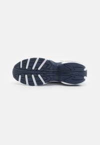 Navy running shoe sole with a textured pattern, featuring white rubber accents and deep grooves for traction and stability.
