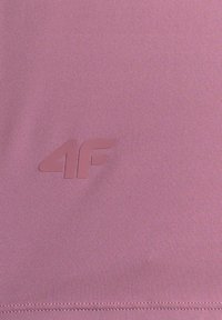 Tissu mauve lisse avec logo 4F embossé de couleur assortie près d’un bord cousu.