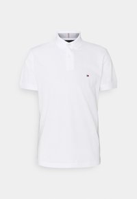 Polo shirt en coton blanc avec un col à boutons, des manches courtes et un petit logo coloré sur la poitrine gauche. Tissu texturé avec une finition lisse.