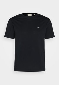 T-shirt en coton noir avec col rond, manches courtes et petit logo blanc sur le côté gauche de la poitrine. Texture lisse et coupe standard.