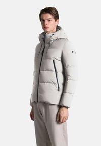 Graue Pufferjacke mit Kapuze, Reißverschlusstaschen und strukturiertem Finish. Verfügt über ein tailliertes Design und eine gestickte Musterung zur Isolierung.