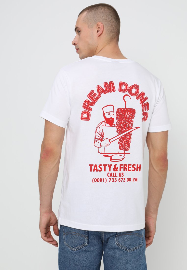 Bjela majica s crvenim grafikonom kuhara s döner kebabom, natpis "DREAM DÖNER", "UKUSNO & SVJEŽE" i kontaktni broj.