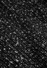 Textured black fabric with a speckled pattern, featuring white and grey threads, creating a varied, soft appearance. Suitable for various applications.