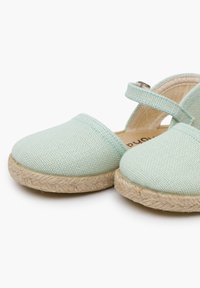Heledad rohelised kanvasest espadrillid, millel on punutud jootekummid, ristivööndi disain ja peened õmblusdetailid.