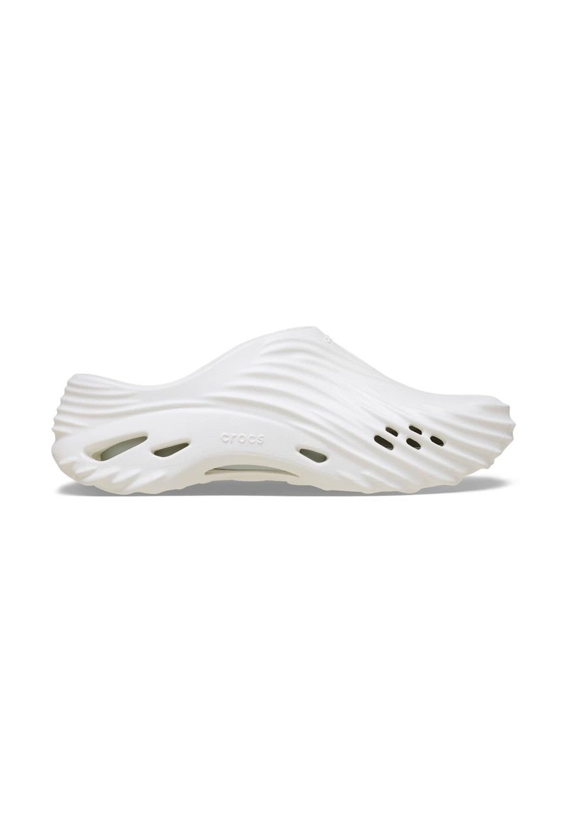 Witte instap-schoenen met een golvend ontwerp, gemaakt van lichtgewicht materiaal. Voorzien van ventilatiegaten en een gladde, ronde vorm.