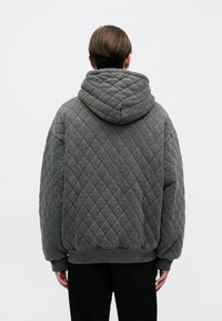 Sudadera con capucha de tejido acolchado en gris con un patrón de diamantes texturizado, una gran capucha, hombros caídos y puños y dobladillo acanalados.