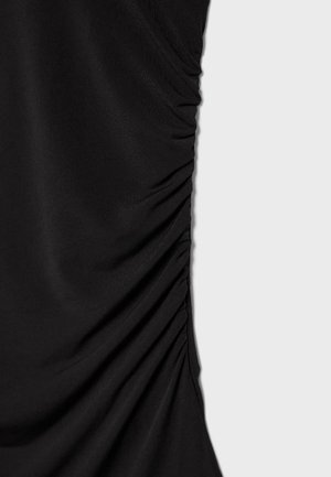 Tessuto nero con dettagli arricciati e plissettati lungo il lato destro su uno sfondo grigio chiaro uniforme.