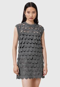 Rochie fără mâneci, de culoare neagră, cu un model circular stratificat, având un țesătură texturată și un tiv in undă. Detalii decupate vizibile pe întreaga rochie.