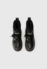 Melna ūdensnecaurlaidīga potīšu zābaki ar mākslīgās kažokādas oderi, quilted sintētisko augšdaļu, bieza gumijas zole un melnas šnores uz minimālisma fona.