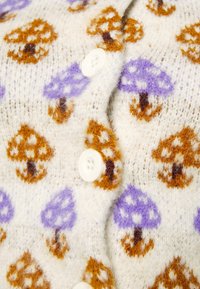 Kardigan i ullblandning med en krämfärgad bakgrund och mönster av bruna och lila svampar. Inkluderar vita knappar och en mjuk textur.