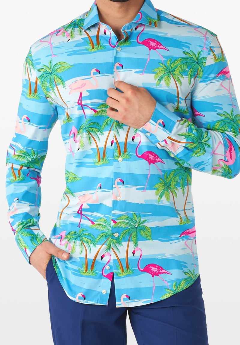 Camisa de botones colorida que presenta un fondo azul con flamencos tropicales y palmeras. Elaborada con una tela ligera y un diseño estampado.