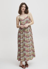 Rochie maximă florală cu bretele subțiri, având un model cu flori roșii, galbene și albe pe un fond deschis; confecționată dintr-un material ușor.