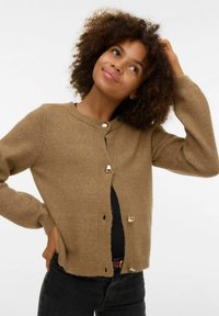 Rjavi pleteni kardigan z okroglim izrezom, z zlatimi gumbi in dolgimi rokavi. Tkanina je videti mehka in teksturirana.