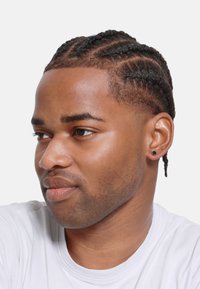 Braided hairstyle with closely cropped sides, dark curls, light brown skin tone, and a small black stud earring. Wearing a white t-shirt.