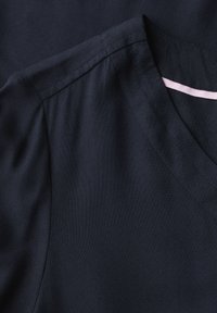 Tessuto blu navy con una superficie liscia e design a V. Presenta un accento rosa in contrasto vicino al collo.