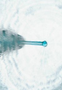 Transparante pipet met een turquoise bol, uitstralend vanuit een taps toelopende, heldere schacht, die rimpelingen creëert op een witte achtergrond.