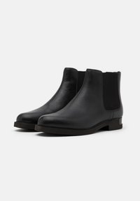 Black leather Chelsea boots featuring elastic side panels, a rounded toe, and a low block heel. Smooth texture with minimal accents.