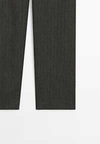 Pantalon gris foncé à rayures fines, coupe droite, avec un motif discret de fines rayures verticales marron sur fond blanc.