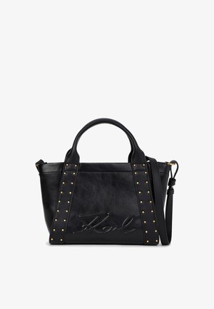 Černá kožená kabelka s dvojitými držadly, nastavitelným ramenním popruhem, zlatými hroty podél předních popruhů a vyraženým podpisem na přední straně.