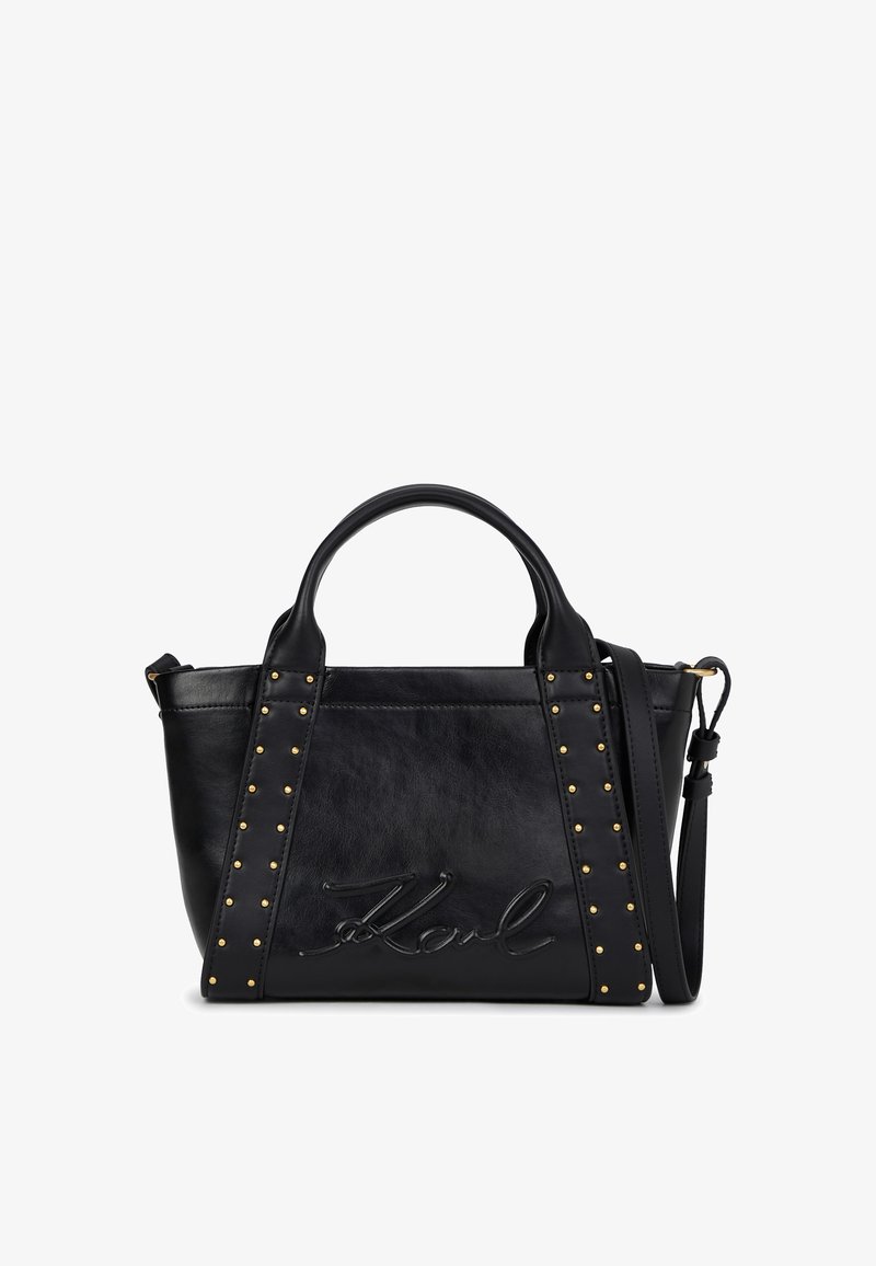 Bolsa de mão em couro preto com alças duplas, alça de ombro ajustável, tachas douradas ao longo das alças frontais e assinatura estampada no painel frontal.