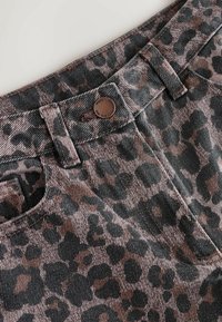 Leopardmønstret kordfløjlstof med mørkegrønne og brune nuancer. Inklusive en metalknap og syede detaljer på taljen og lommerne.